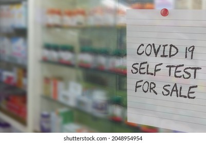 Selective Focus On Note With Text Covid19 Self Test For Sale In A Pharmacy Or Drugstore With Blurred Shelves In Background. Concept For Self Testing, Auto Test