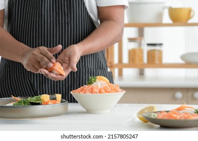 Selective focus on old man chef hand making salmon sushi and prepare sliced salmon sashimi on ice in bowl served with wasabi, sliced lemon and radish at kitchen. Japanese food home cooked concept - Powered by Shutterstock