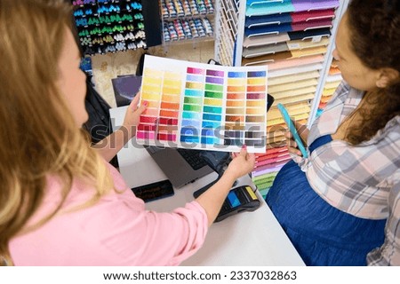 Selective focus on a palette with color swatches of watercolor paints of various spectrums, in the hands of a saleswoman demonstrating it to customer shopping in a stationery store. Painting and art