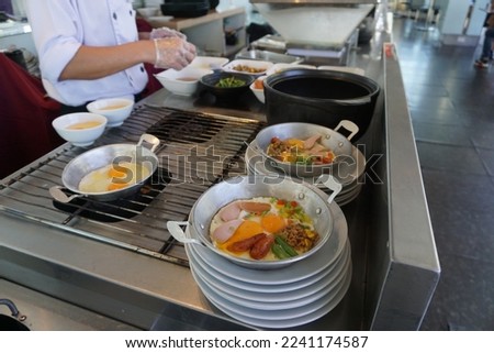 Selective focus on pan-fried egg with toppings in the bottom right corner that the chef has just cooked and ready to serve.