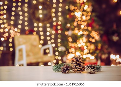 Selective Focus On Pine Cones, Blurred Living Room With Decorated  Christmas Tree And Chair. Lot Of Fairy Lights Illuminated. Christmas Theme Products Or Greeting Card Background, Lot Of Copy Space.