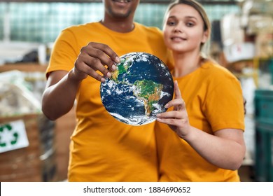 Selective focus on planet earth model in hands of young multiracial couple of waste station workers. Garbage sorting and recycling concept - Powered by Shutterstock