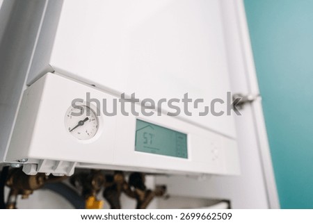 Selective focus on pressure sensor on gas boiler. Utility room features a modern domestics appliances with a digital display and pressure gauge. Efficient temperature control and household heating