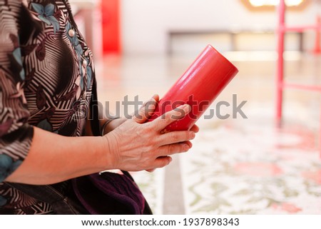 Selective focus on red fortune sticks wooden box or Kau Cim with Asian woman hands shake Chinese Fortune Sticks pray for good fortune