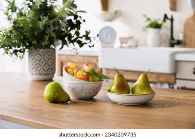 selective focus on ripe pears on plate, grape in ceramic bowl and flowers in vase on wooden dining table on home kitchen background. fresh fruits on tabletop. healthy eating concept. - Powered by Shutterstock