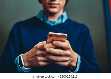 Selective focus on smartphone in hands of pensive hipster guy sending text message indoors,concentrated millennial male checking banking balance via application on telephone and 4G connection