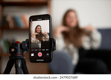 Selective focus on smartphone screen recording plus size blogger influencer on couch streaming live with her subscribers, sharing advice upon losing weight, healthy eating and stories of her life