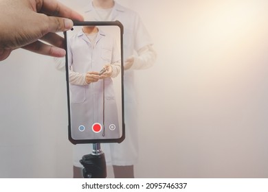 Selective focus on smartphone sharing on social media by asian male doctor live broadcasting education for healthcare viral video clip on white-gray background. Telemedicine or telehealth concept. - Powered by Shutterstock