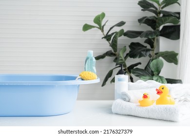 Selective focus on sponge and liquid soap or shampoo bottle are place on blue bathtub. Two yellow ducks toys on towel, talc powder, body lotion are near tub on table. Baby shower accessories concept - Shutterstock ID 2176327379
