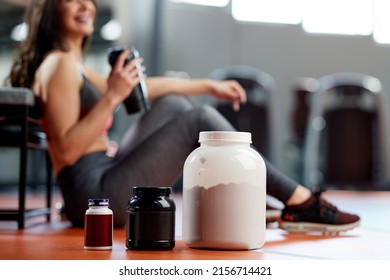 Selective focus on supplements and protein power in gym with a sportswoman.