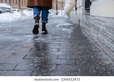 Selective focus on technical salt grains on icy sidewalk surface in wintertime, used for melting ice and snow. Applying salt to keep roads clear and people safe in winter weather from ice or snow