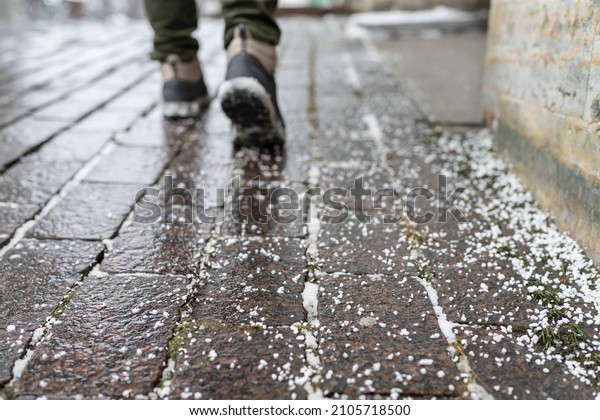 Selective focus on technical salt grains on icy\
sidewalk surface in wintertime, used for melting ice and snow.\
Applying salt to keep roads clear and people safe in winter weather\
from ice or snow