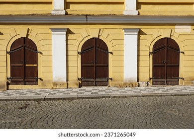 selective focus on three huge semi-circular wooden doors. Yellow stone wall with brown doors