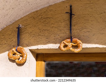 Selective Focus On Two Pretzels With Blue Ribbons On The Bakery Wall. Traditional Beer Snack