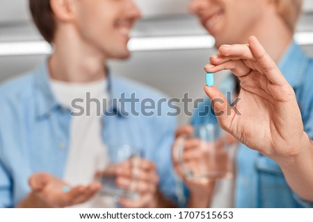 Selective focus on two young adult homosexual guy holding pre exposure HIV protection pills in hands, showing medicament on camera against blurred background with copy space