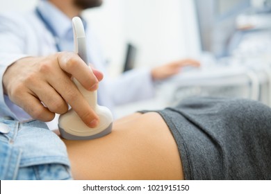Selective focus on ultrasound scanner device in the hand of a professional doctor examining his patient doing abdominal ultrasound scanning sonogram sonography sonographer early pregnancy - Shutterstock ID 1021915150