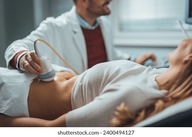 Selective focus on ultrasound scanner device in the hand of a professional doctor examining his patient doing abdominal ultrasound scanning sonogram sonography sonographer early pregnancy - Powered by Shutterstock