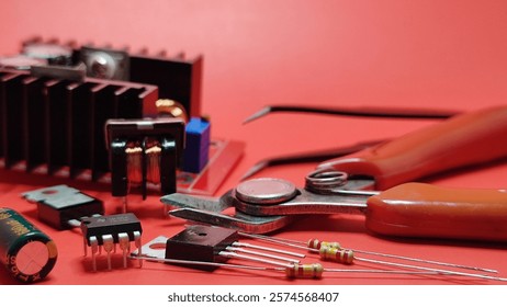 Selective focus on various shaped electronic components and repair equipment with a dark red background and a blurred image of a black electronic circuit board.