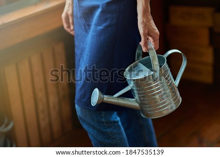 Selective focus on watering can in working woman hand