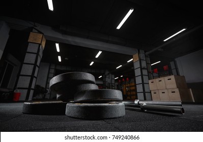 Selective focus on weights and gym equipment on the floor at fitness box weightlifting crossfit box training exercising space interior dark brutal motivation determination concept