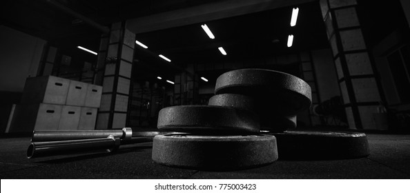 Selective focus on weights and gym equipment on the floor at fitness box weightlifting 
crossfit and fitness box training exercising space interior dark brutal motivation determination concept