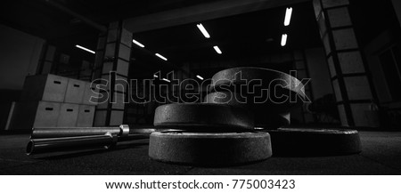 Selective focus on weights and gym equipment on the floor at fitness box weightlifting 
crossfit and fitness box training exercising space interior dark brutal motivation determination concept