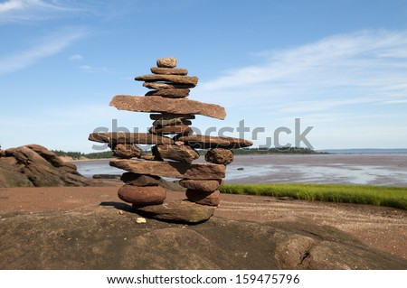 Selective focus on the welcoming Inukshuk in the foreground and Bay of Fundy shoreline in the background