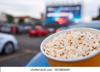 Selective focus on yellow bucket full of popcorn on car parking at drive-in cinema background. Free time, leisure and entertainment concept