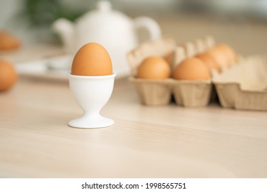 Selective focus at one boiled egg put on the kitchen desk with blurred eggs carton background of kitchen equipment ready to prepare food meal for breakfast. With copy space for add text