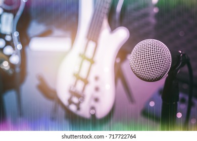 Selective focus one of microphone with the blur of electric bass and guitar.mix variety of instrument on the home music studio recording background concept.Pastel tone and sound wave. 