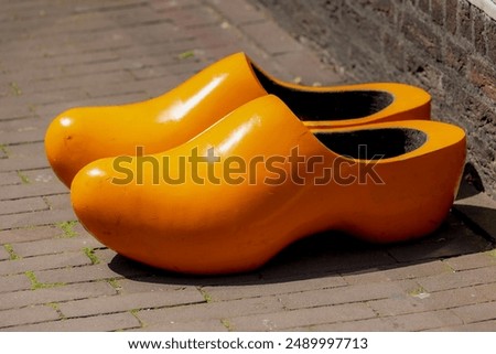 Selective focus of one pair orange wood shoe, Typical handmade wooden shoes on brick street floor, Clogs (Dutch: Klompen) are a type of footwear made in part or completely from wood, Netherlands.