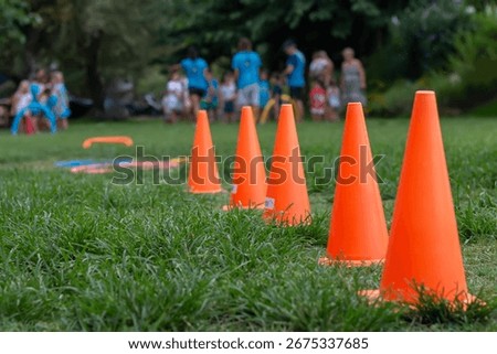Selective focus orange obstacle training hurdle in a row  on green grass filed. Outdoor sport practice on meadow.  Child's play in summer. Sports Festival. Sport and recreation concept. 