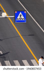 Selective Focus At Overhead Electric Pedestrian Crossing Sign With Elderly Man Is Walking On Zebra Crosswalk In Vertical Frame