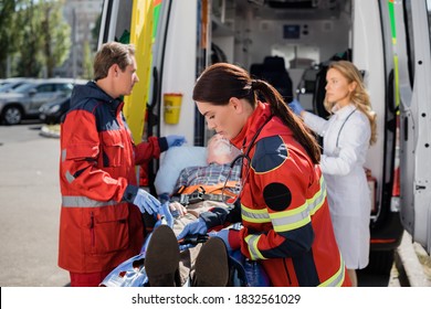 Selective Focus Of Paramedic Fastening Belts Near Patient On Stretcher And Colleagues On Urban Street