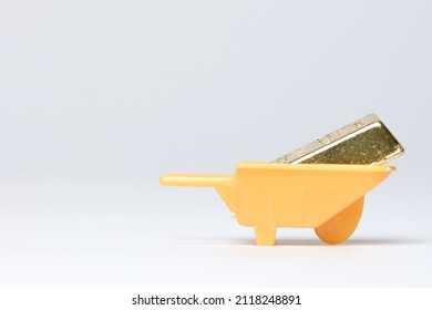 Selective Focus Part Of Gold Bar Miniature With Wheelbarrow Insight. Wealth Creation Concept.
