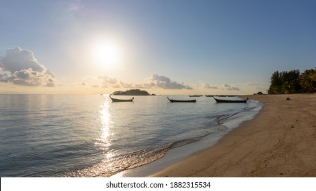 Selective Focus Of A Peaceful Beach During Sun Rise With Golden Light And Blue Sky. Fishing Boat Background