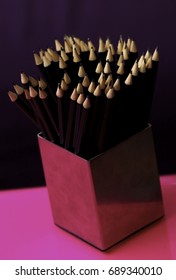 Selective Focus. Pencil group in a container on a pink table with a dark background.