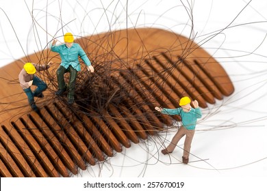 selective focus photo of miniature workers holding hair loss from wooden comb, abstract background to solution hair loss concept.

