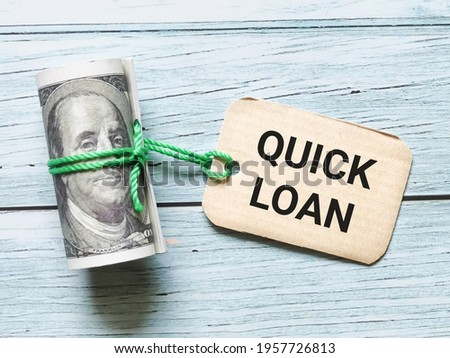 Selective focus phrase QUICK LOAN written on label tag with fake money. Business and finance concept.