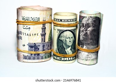 Selective focus of a pile of American dollars rolls with rolled up Egyptian money banknote bills of 100 LE, 200 LE one hundred and two hundred pounds, USA dollar and Egyptian pound exchange rate