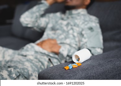 Selective Focus Of Pills And Tired African American Soldier Suffering From PTSD At Home, Cropped View