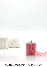 Selective focus of pink thread spools with pink flowers on white background. Isolated