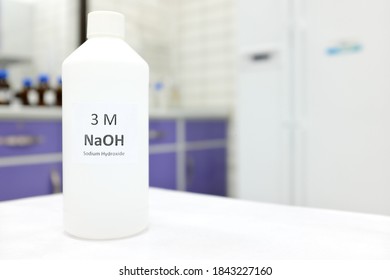 Selective Focus Of A Plastic Bottle Of Sodium Hydroxide Solution Or NaOH Chemical Reagent. Chemistry Research Laboratory Background With Copy Space.