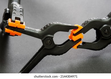 Selective focus of plastic clamps holding each other on Black Isolated background. Compressing, holding, fixing concept. Abstract concept of deception, addiction, struggle, hindrance, pursuit. - Shutterstock ID 2144304971