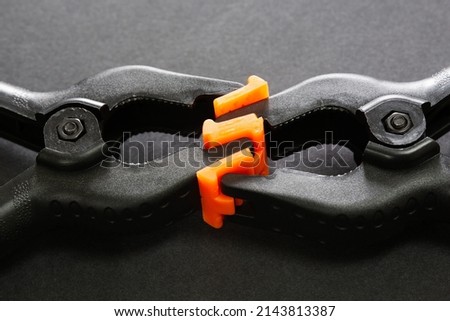 Selective focus of plastic clamps holding each other on black isolated background. Abstract concept of love, romance, passion, attachment, hugging.