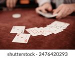 Selective focus of Playing cards displayed on a Poker Table while a Deck of Cards is shuffled in the background
