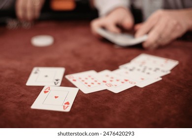 Selective focus of Playing cards displayed on a Poker Table while a Deck of Cards is shuffled in the background - Powered by Shutterstock