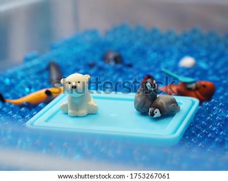 Selective focus of polar bears and penguins, arctic animals mini figures in blue hydrogel water beads. Kids activities and education concept.