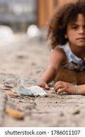 Selective Focus Of Poor African American Kid Reaching Dirty Medical Mask Near Curly Sister