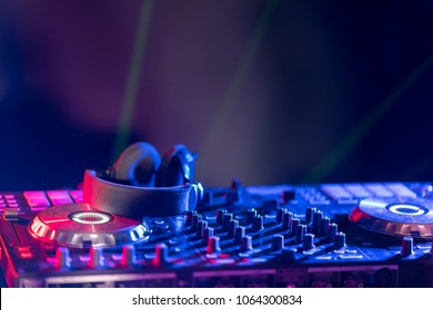 In selective focus of Pro DJ controller.The DJ console CD mp4 deejay mixing desk Ibiza house music party in nightclub with colored disco lights.